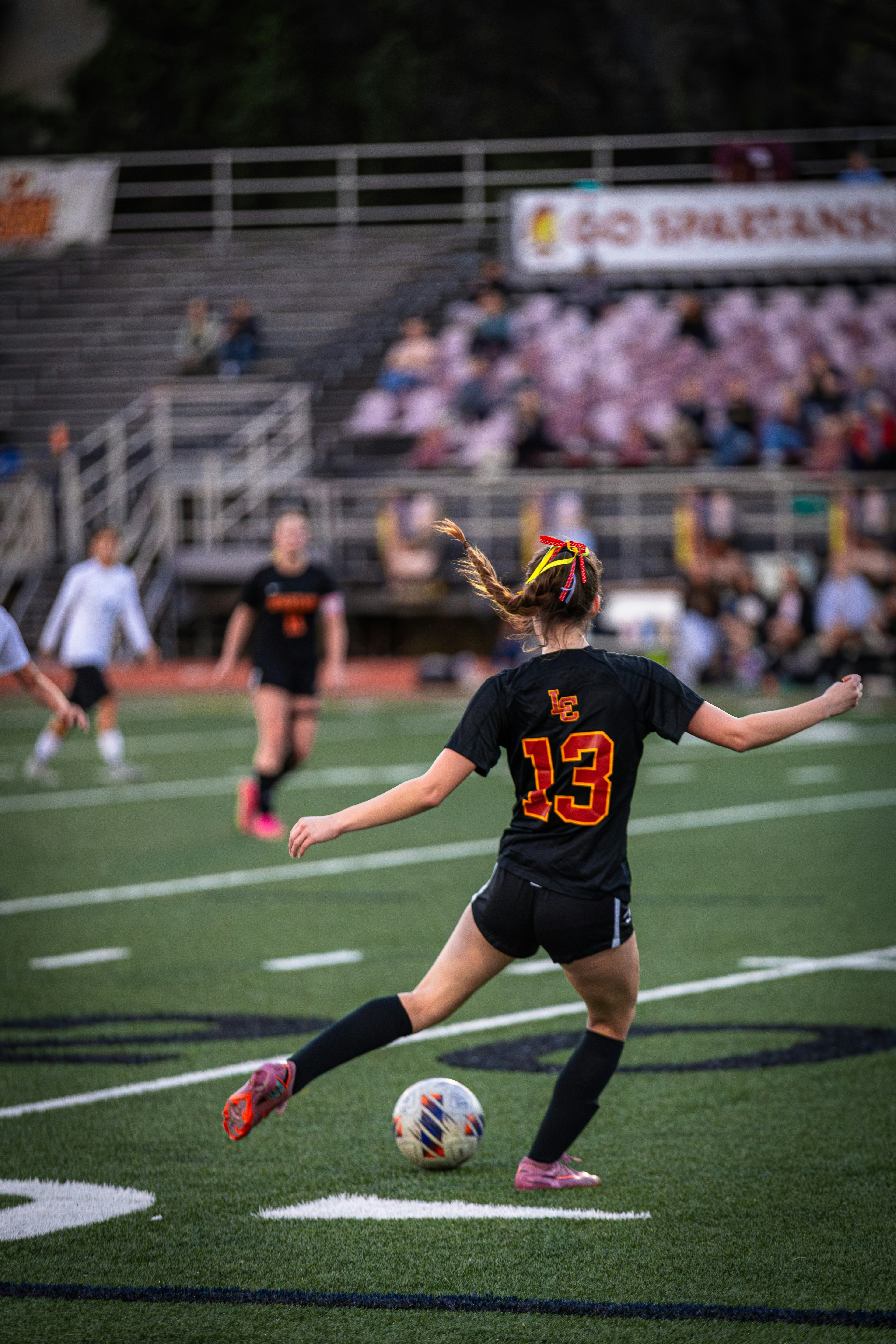Soccer player in action on a field with spectators in the stands.